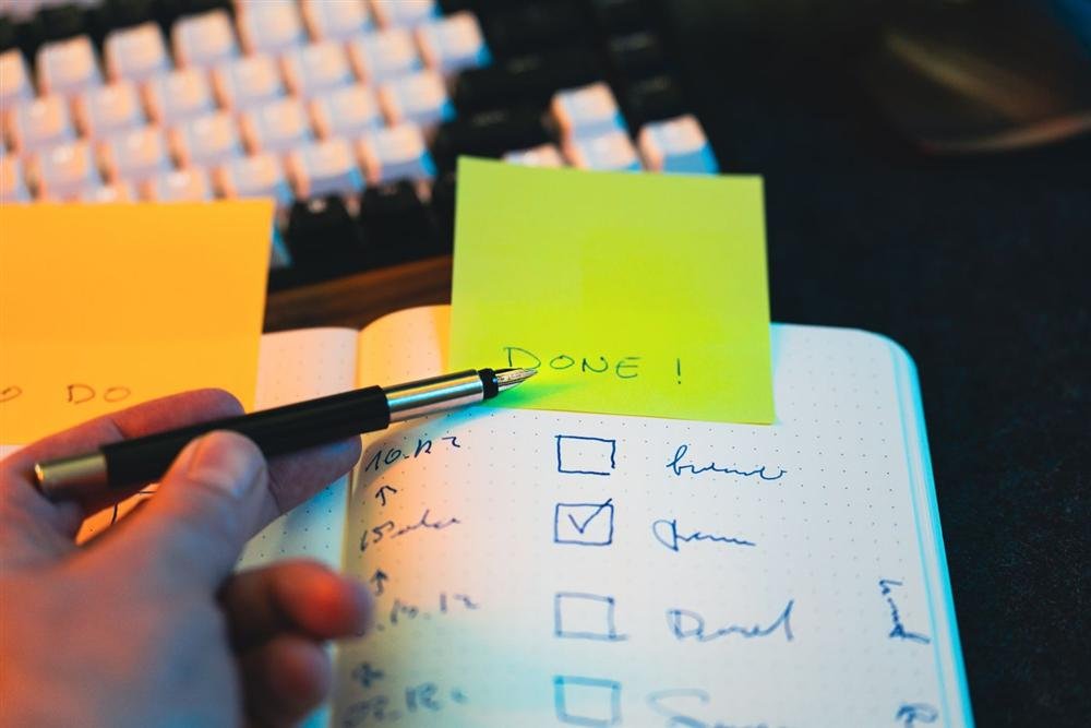 Hand holding a pen over a notebook checklist with completed tasks