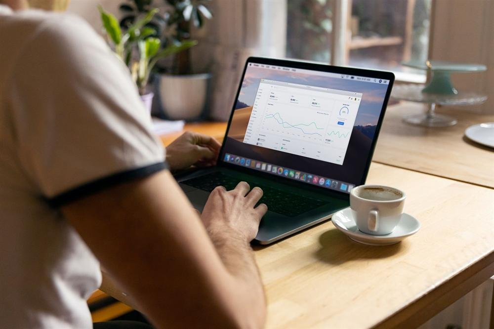 Person checking analytics on a laptop with coffee in a home office
