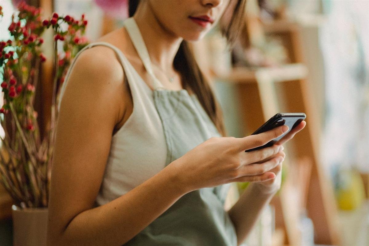Shop owner browsing their phone while working in a small floral shop