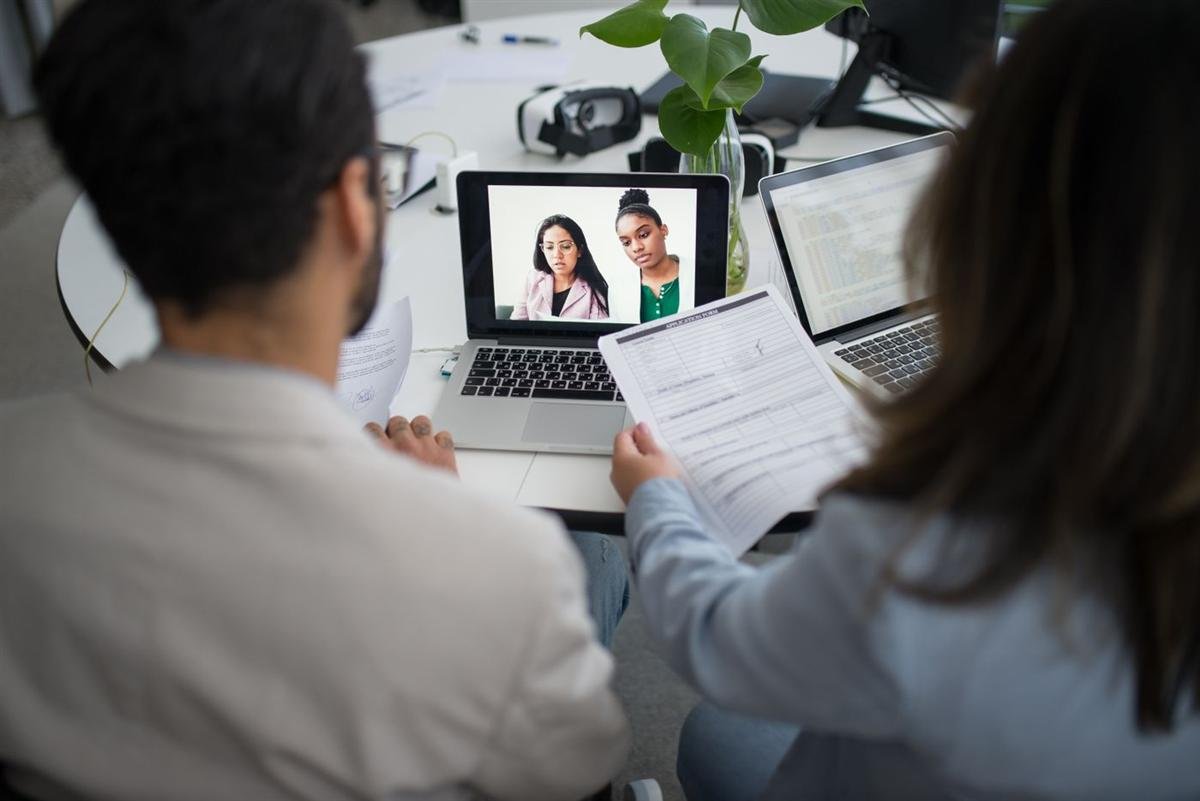 Two professionals conducting a video interview on laptops in a modern office
