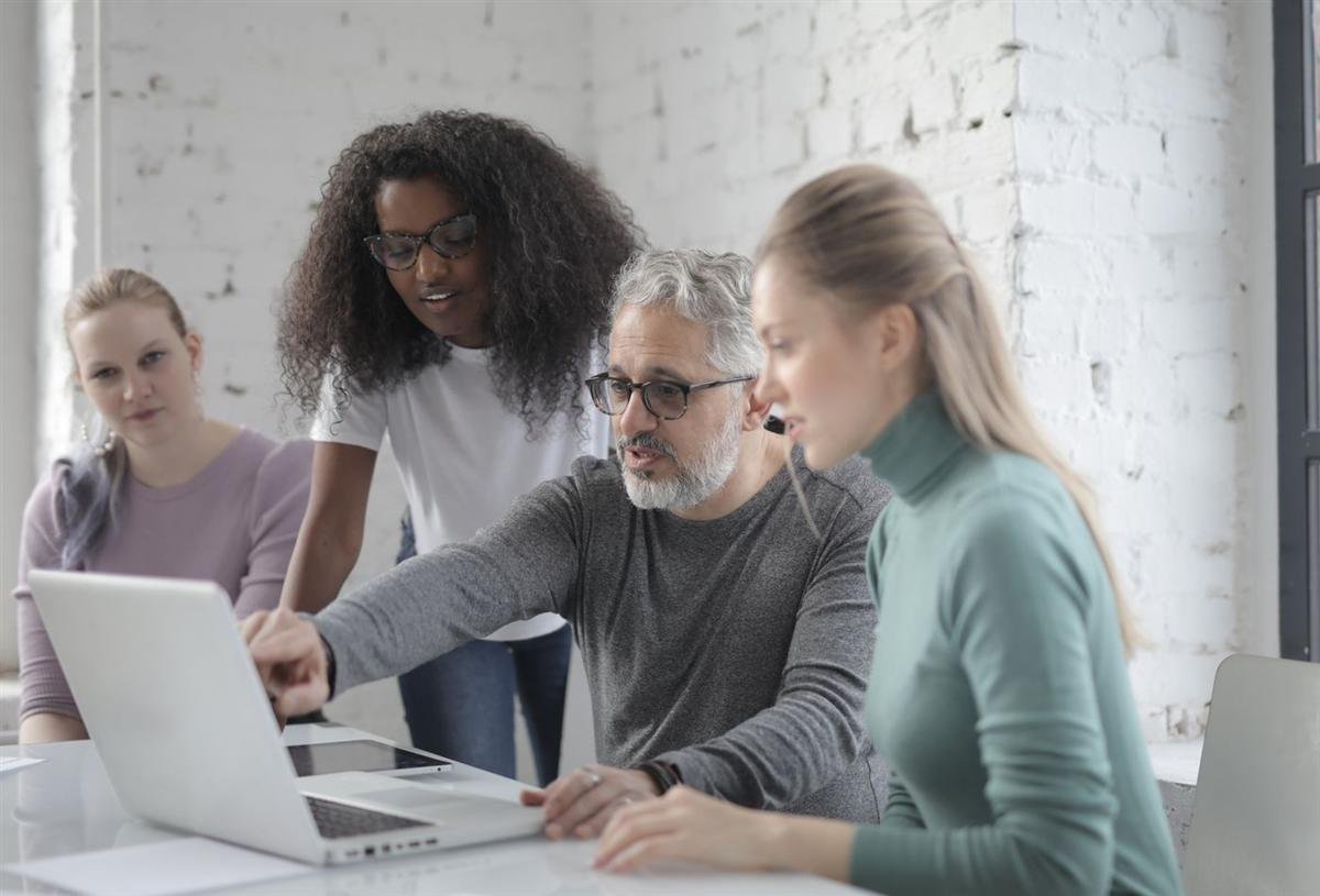 People gathered around a laptop discussing a website project