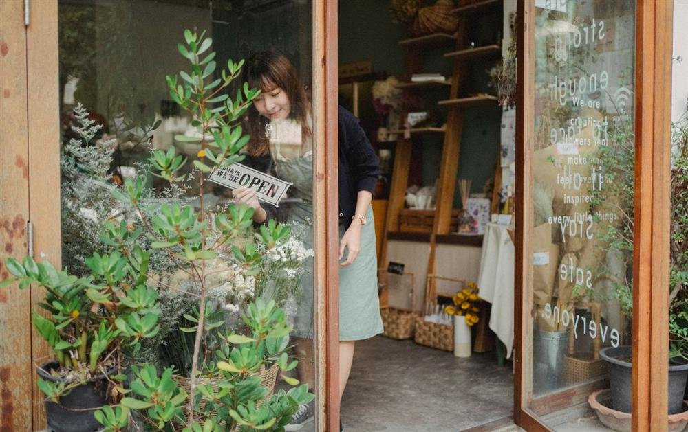Shop owner turning an open sign on the glass door of a small shop