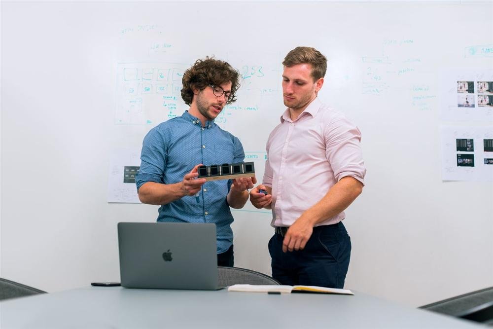 Two people in an office reviewing a project on a laptop together